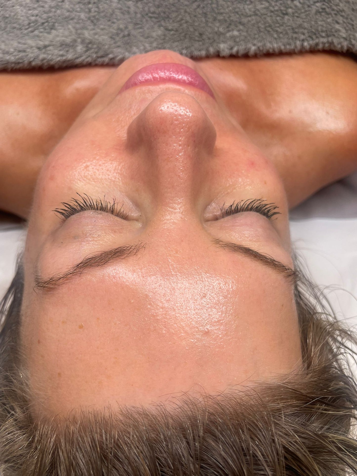 Close-up of a woman with clear glowing skin lying down during a luxury facial treatment in Swindon spa.