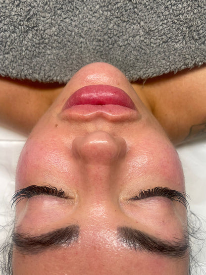 Close-up of a woman’s face with closed eyes receiving a luxury facial treatment on a spa bed.