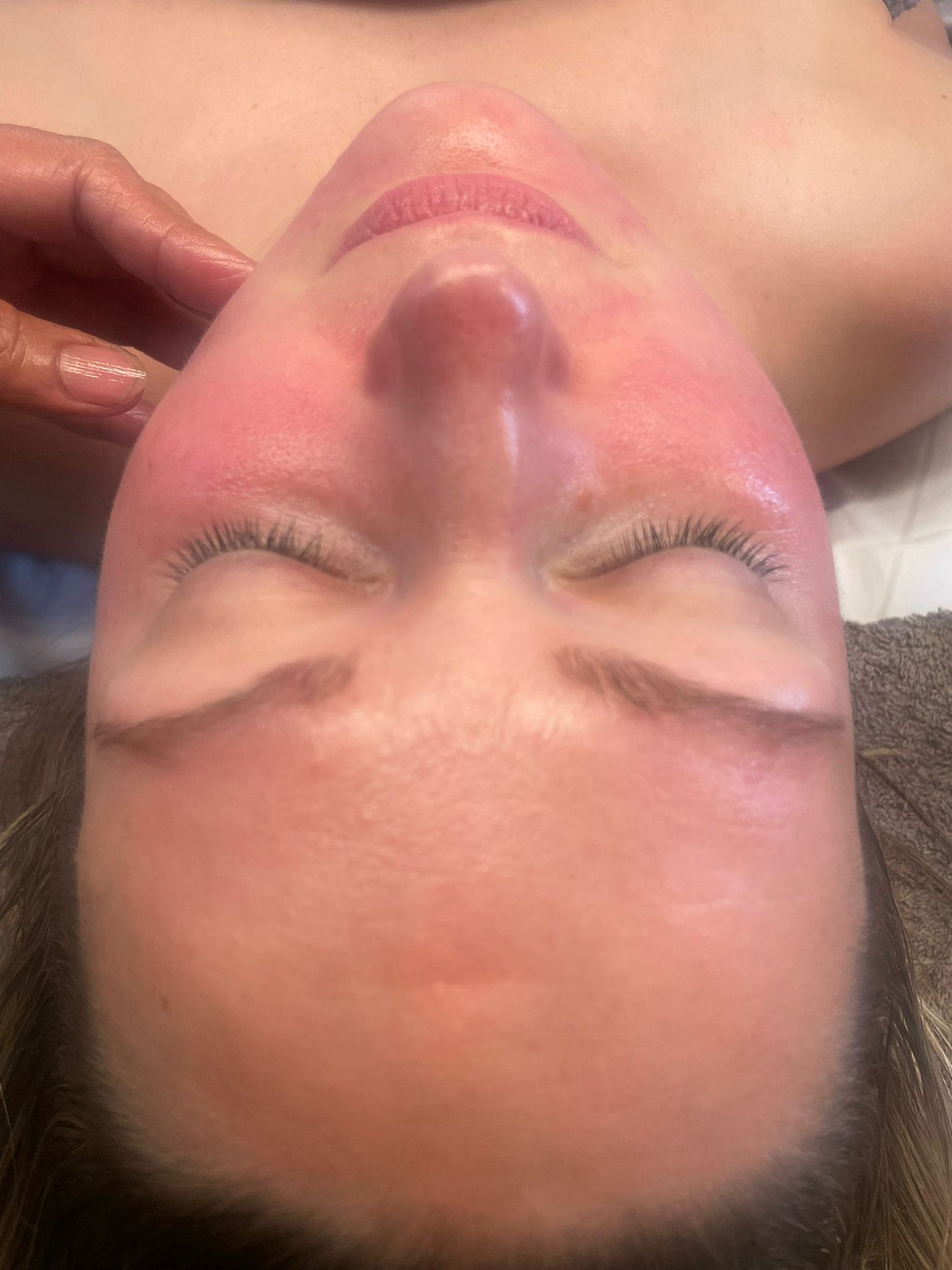 Close-up of a woman receiving a relaxing facial treatment with glowing, refreshed skin in a beauty salon setting.