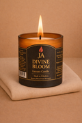 Lit Divine Bloom luxury candle in amber glass jar on beige fabric, creating a cozy and elegant home ambiance