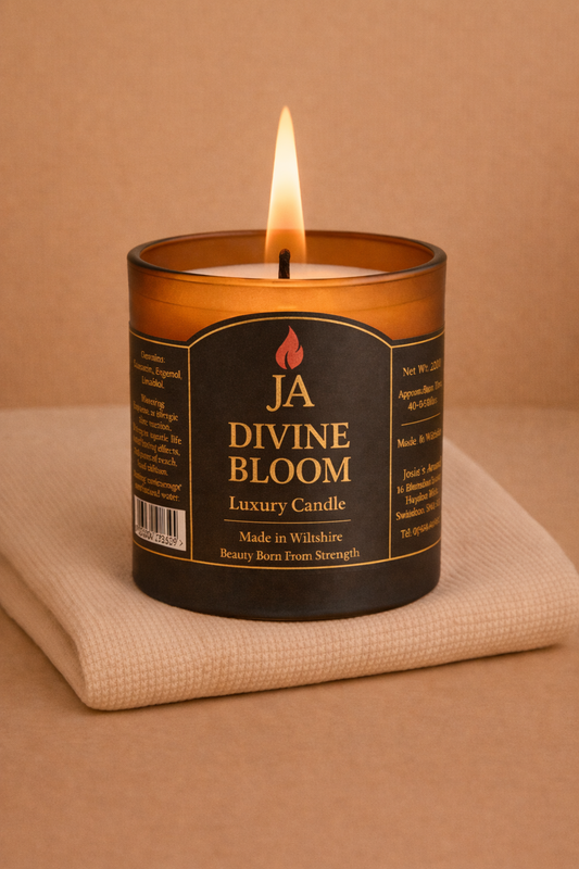 Lit Divine Bloom luxury candle in amber glass jar on beige fabric, creating a cozy and elegant home ambiance