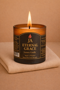 Lit Eternal Grace luxury candle in amber glass on a soft beige cloth, creating a calming cozy atmosphere.
