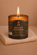 Burning BRIGHT HORIZON luxury lemongrass and ginger candle in amber glass jar on beige fabric background