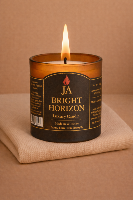 Burning BRIGHT HORIZON luxury lemongrass and ginger candle in amber glass jar on beige fabric background