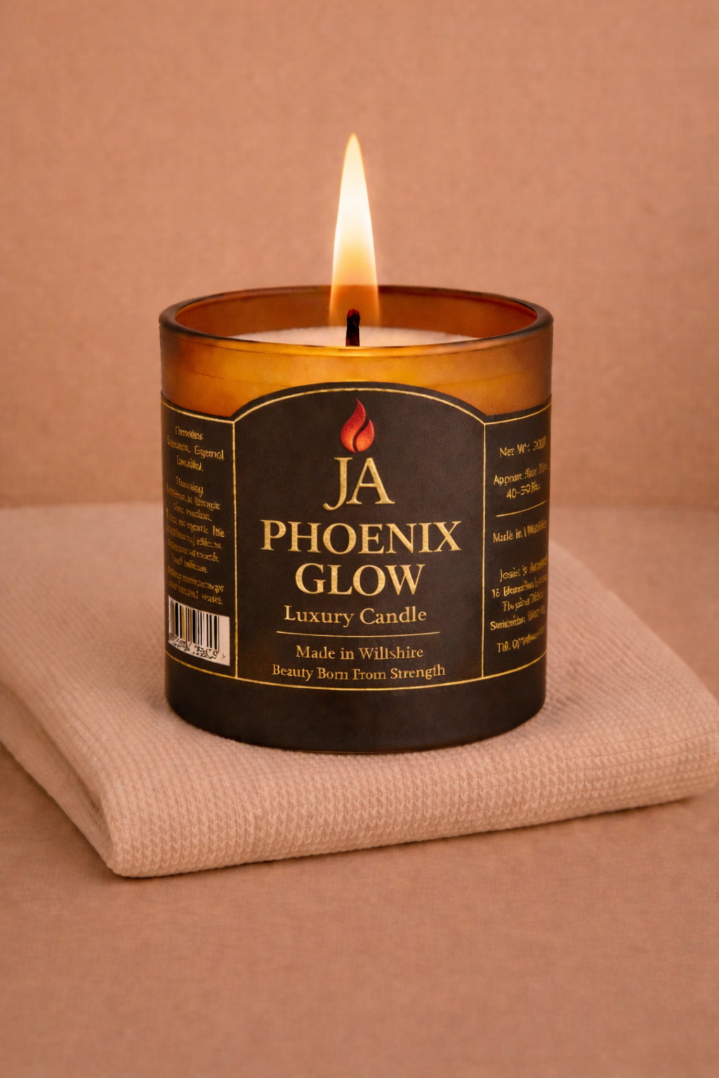 Lit JA Phoenix Glow luxury coconut scented candle on beige cloth with warm background tone