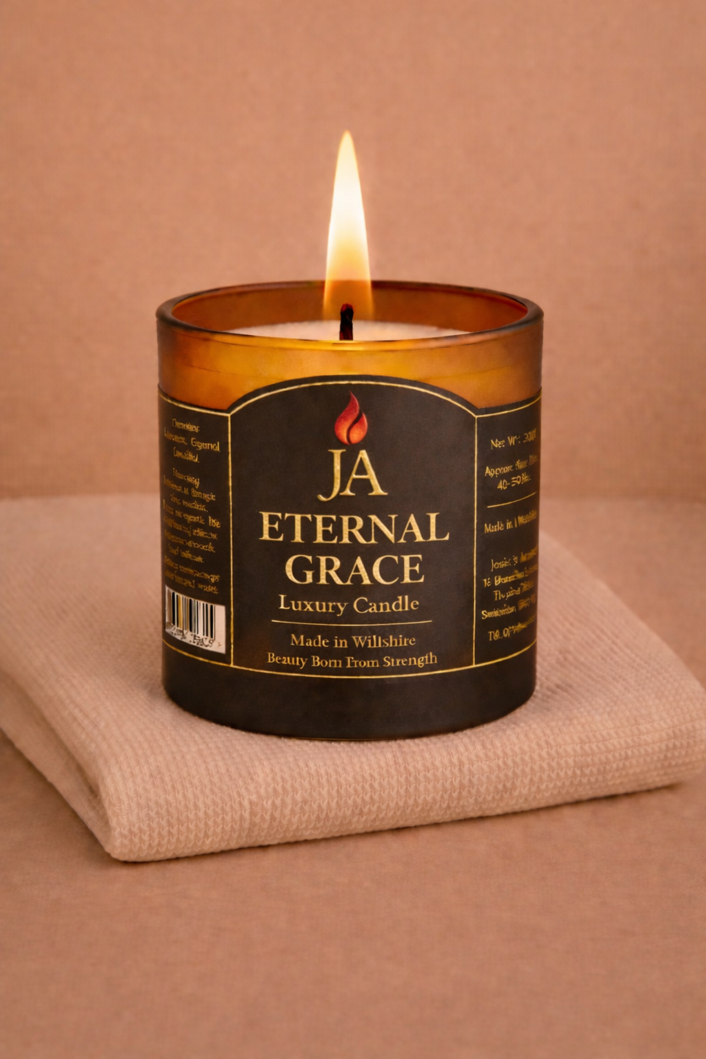 Burning Eternal Grace luxury rosewood and velvet scented candle in amber glass jar on beige fabric